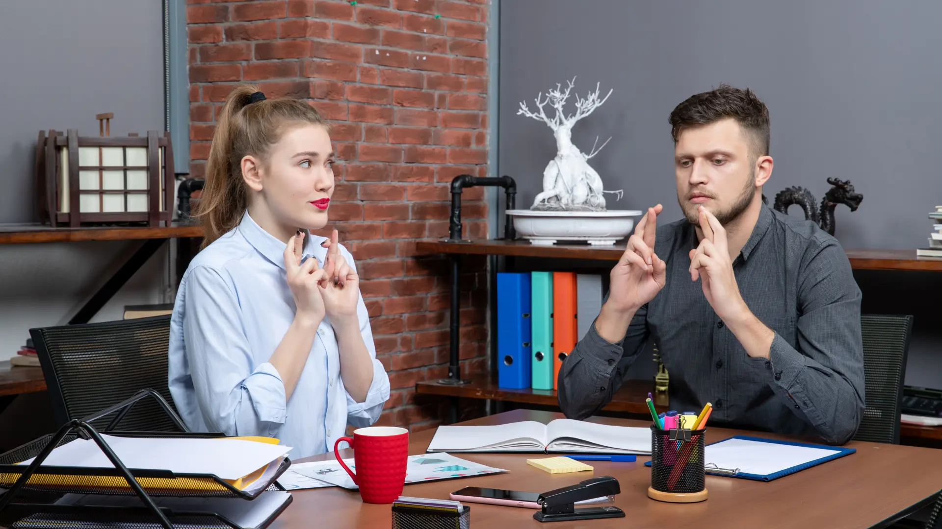 Two candidates practicing interview body language with steady eye contact, posture and purposeful hand gestures