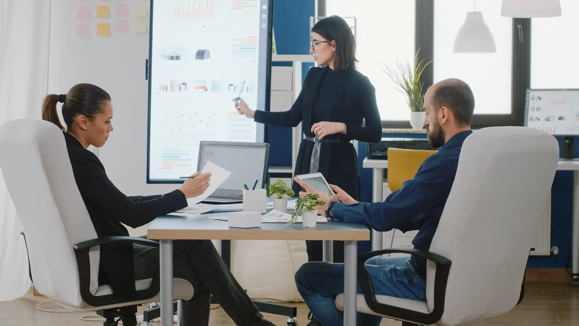 Three professionals in a meeting demonstrate confident posture, eye contact and natural gestures during a presentation